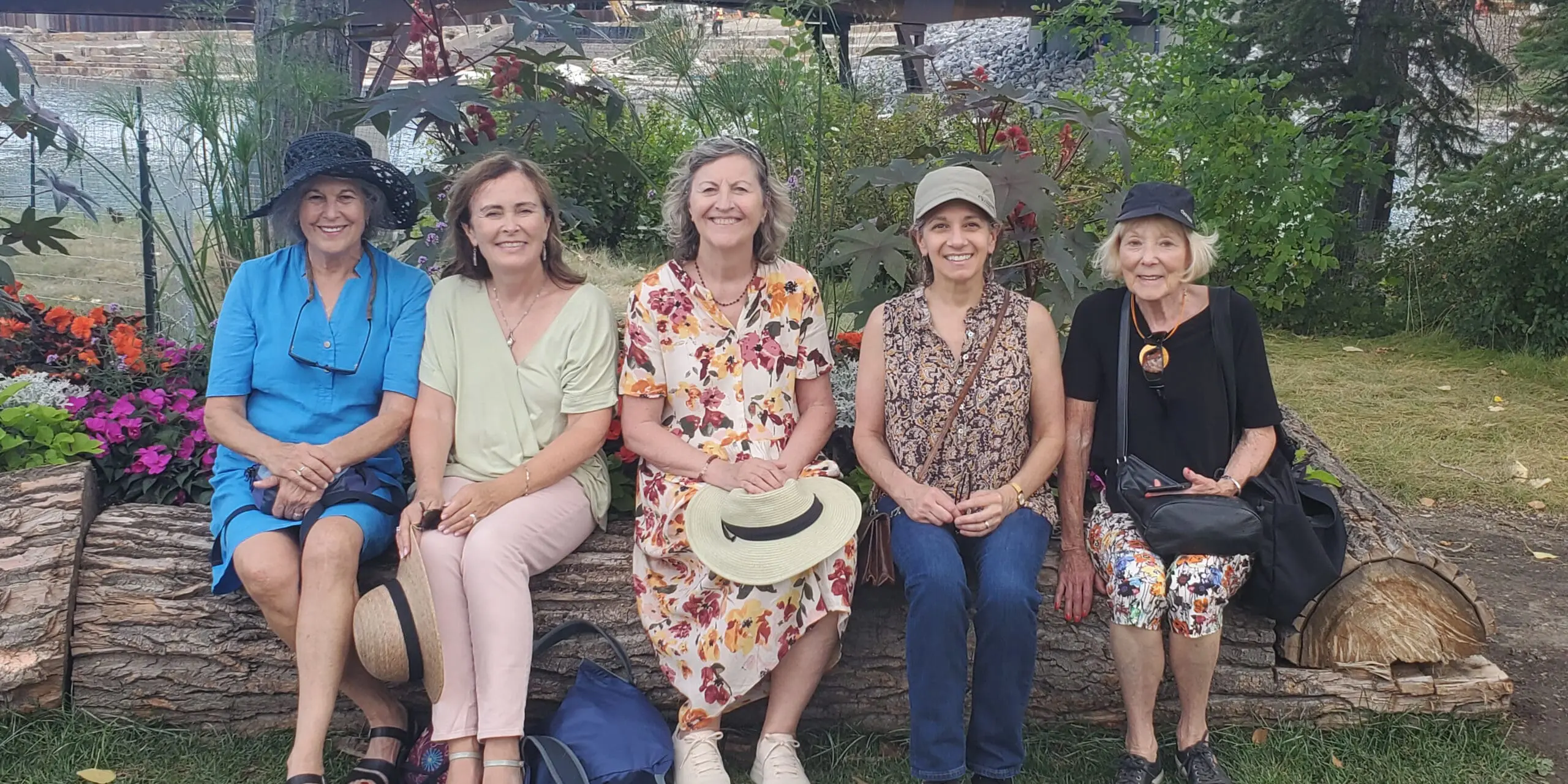 Five older women sitting on a bench in a park