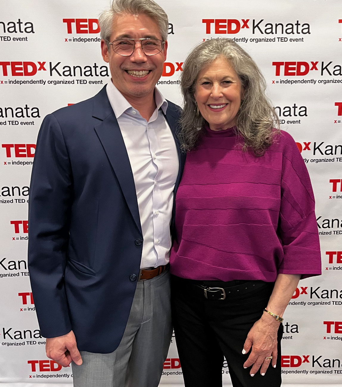 A woman and a man standing in front of a TEDx Kanata background